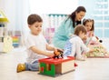 Children with teacher in daycare. Kids play with toys in kindergarten. Little boy playing with car and parking garage. Royalty Free Stock Photo