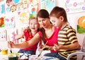 Children with teacher draw paints in play room. Royalty Free Stock Photo