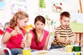 Children with teacher draw paints in play room. Royalty Free Stock Photo