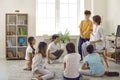 Group of happy school students sitting on the floor during circle time with their teacher Royalty Free Stock Photo