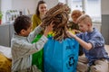 Children with teacher separating rubbish in to three bins. Royalty Free Stock Photo