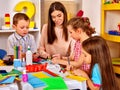 Children with teacher woman painting on paper in kindergarten .