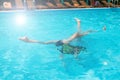 Children teenagers girls have fun swimming and diving in the outdoor pool, feet up over the water, splashing, sunlight, glare, Royalty Free Stock Photo