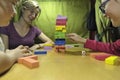 Children with their mother playing together to remove wooden blocks, fun and risky Royalty Free Stock Photo