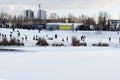 Children and their parents sledding from a snow slide in a city park with a frozen lake in Kiev Ukraine