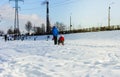 Children and their parents sledding from a snow slide in a city park with a frozen lake in Kiev Ukraine