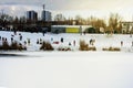 Children and their parents sledding from a snow slide in a city park with a frozen lake in Kiev Ukraine
