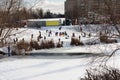 Children and their parents sledding from a snow slide in a city park with a frozen lake in Kiev, Ukraine