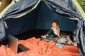 Children tourism. Child using laptop in the tent at the campsite. Girl watching cartoon on gadget. Kid girl in a campaign in a