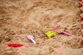 Children toys lie forgotten in an empty sandbox. A shovel, a rake and a