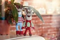 Two stylish amigurumi deers in striped sweaters, scarf and butterfly tie standing near flowerpot. Royalty Free Stock Photo