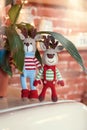 Children toys. Two stylish amigurumi deers in striped sweaters, scarf and butterfly tie standing near flowerpot