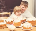Children with traditional Easter homemade cakes and colored eggs. Teen boy and little girl sitting at the table full of Royalty Free Stock Photo