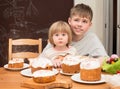 Children with traditional Easter homemade cakes and colored eggs. Teen boy and little girl sitting at the table full of Royalty Free Stock Photo