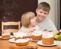 Children with traditional Easter homemade cakes and colored eggs. Teen boy and little girl sitting at the table full of Royalty Free Stock Photo