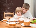 Children with traditional Easter homemade cakes and colored eggs. Teen boy and little girl sitting at the table full of Royalty Free Stock Photo