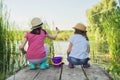 Children two girls together playing with water on lake on wooden pier in reeds Royalty Free Stock Photo