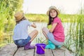 Children two girls together playing with water on lake on wooden pier in reeds Royalty Free Stock Photo