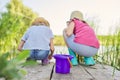 Children two girls together playing with water on lake on wooden pier in reeds Royalty Free Stock Photo