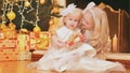 Children two little girls sisters sitting with gifts at home on the background of Christmas tree and fireplace Royalty Free Stock Photo