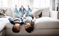 Children upside down, playful and happy at family home for fun with sibling, brothers on sofa and relax in living room