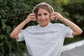 Children urban lifestyle concept. Girl in headphones listen to music walk in green park outdoors with green trees on