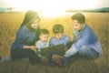 Children use a laptop with their parents in meadow Royalty Free Stock Photo