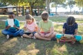 Children using tablet computer while sitting on grassy field Royalty Free Stock Photo