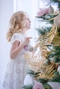 Children Waiting for the New Year and Christmas. Cute little girl decorating christmas tree by baubles at home.