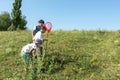 Children walk in a field on clear spring or a summer day. They catch butterflies or insects with a butterfly net