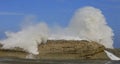 Children watching large wave crashing over rock