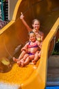 Children at water park slide down and show thumbs up. Royalty Free Stock Photo