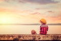 Children wear hat and red jacket sitting lonely on the ground. Royalty Free Stock Photo