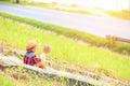 A children wear hat and sitting on stair. A children hold flower and near the road.