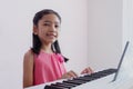 The children wear a pink dress practice the piano with enjoy and smiling