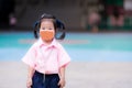 Children wearing brown cloth face masks to protect virus. Asian girl stands in school grounds. Student go to school with new
