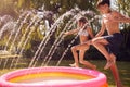 Children Wearing Swimming Costumes Having Fun In Garden Playing In Water From Garden Sprinkler Royalty Free Stock Photo