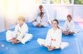 Children in white kimono sits in butterfly pose and practices stretching in sport gym
