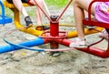 Children who spin on a low circular carousel in the Playground. Parts of the legs of sitting children