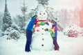 Children in a winter snowy forest mold a big snowman.Family winter fun for Christmas vacation