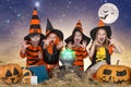 Halloween.The children of witches and wizards cooking potion in the cauldron with pumpkin and spell book. Royalty Free Stock Photo