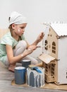 Children at work: The girl neatly paints the facade of the doll house with a small tassel in white. Royalty Free Stock Photo