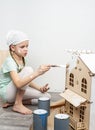 Children at work: The girl neatly paints the facade of the doll house with a small tassel in white. Royalty Free Stock Photo