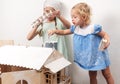 Children at work: Two girls sisters paint the roof of the doll house in white. The youngest girl intently makes smears