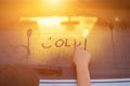 Children writing word COLD on wet rear mirror of her father SUV car