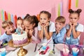 Children wth fists under their chind standing around the cake