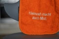 Children's bib with inscription "Little things make also a mess" hanging on a baby high chair
