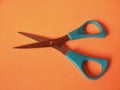 Children's blue scissors on orange background.