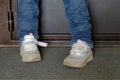 children& x27;s feet in blue jeans in worn baby shoes on the mat in front of the door Royalty Free Stock Photo