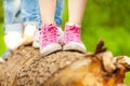 Children's feet in pink sneakers standing on a log